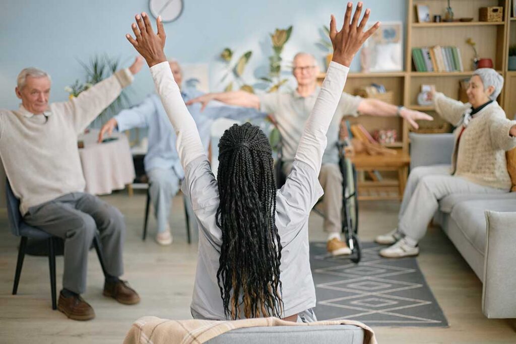 A senior resident with a white cane walking confidently down a well-lit, thoughtfully arranged hallway.