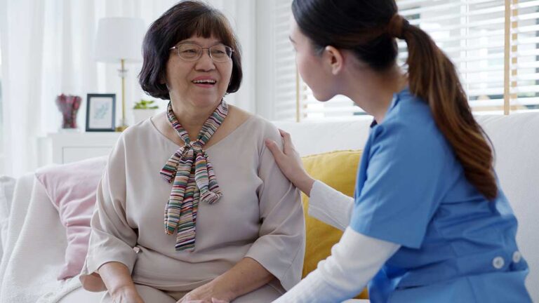 Caregiver reviews a personalized care plan with an older resident at a bright assisted living table.